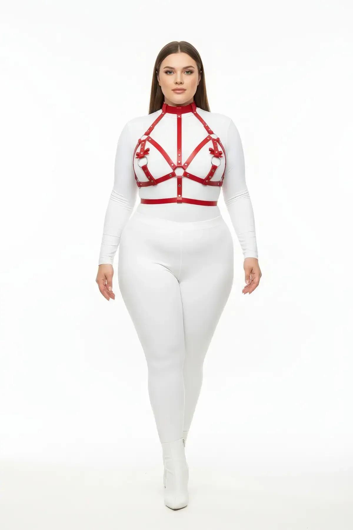 Red faux leather strappy chest harness with three silver O-rings, adjustable cage silhouette worn over white long-sleeve top