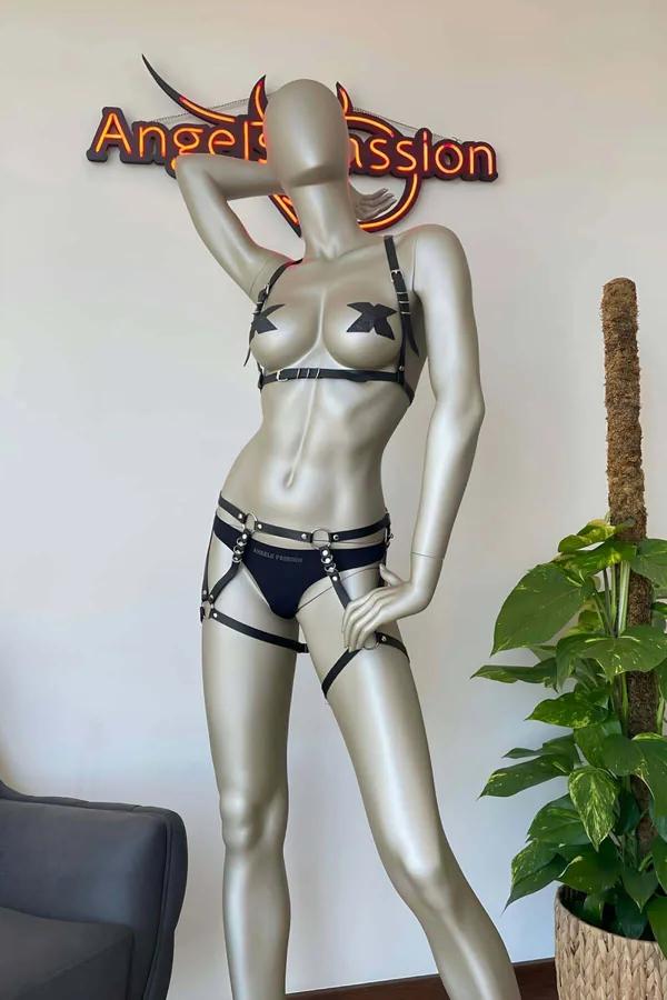 Black faux leather harness lingerie set with silver O-rings, studded brief, and adjustable thigh garter straps on mannequin