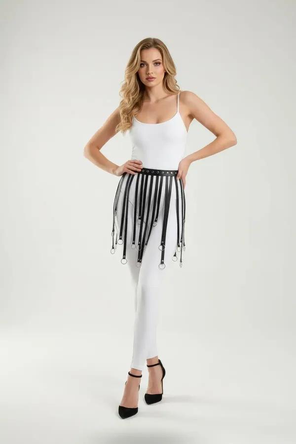 Black faux leather fringe garter skirt with silver O-ring strap tips worn over white leggings, front view