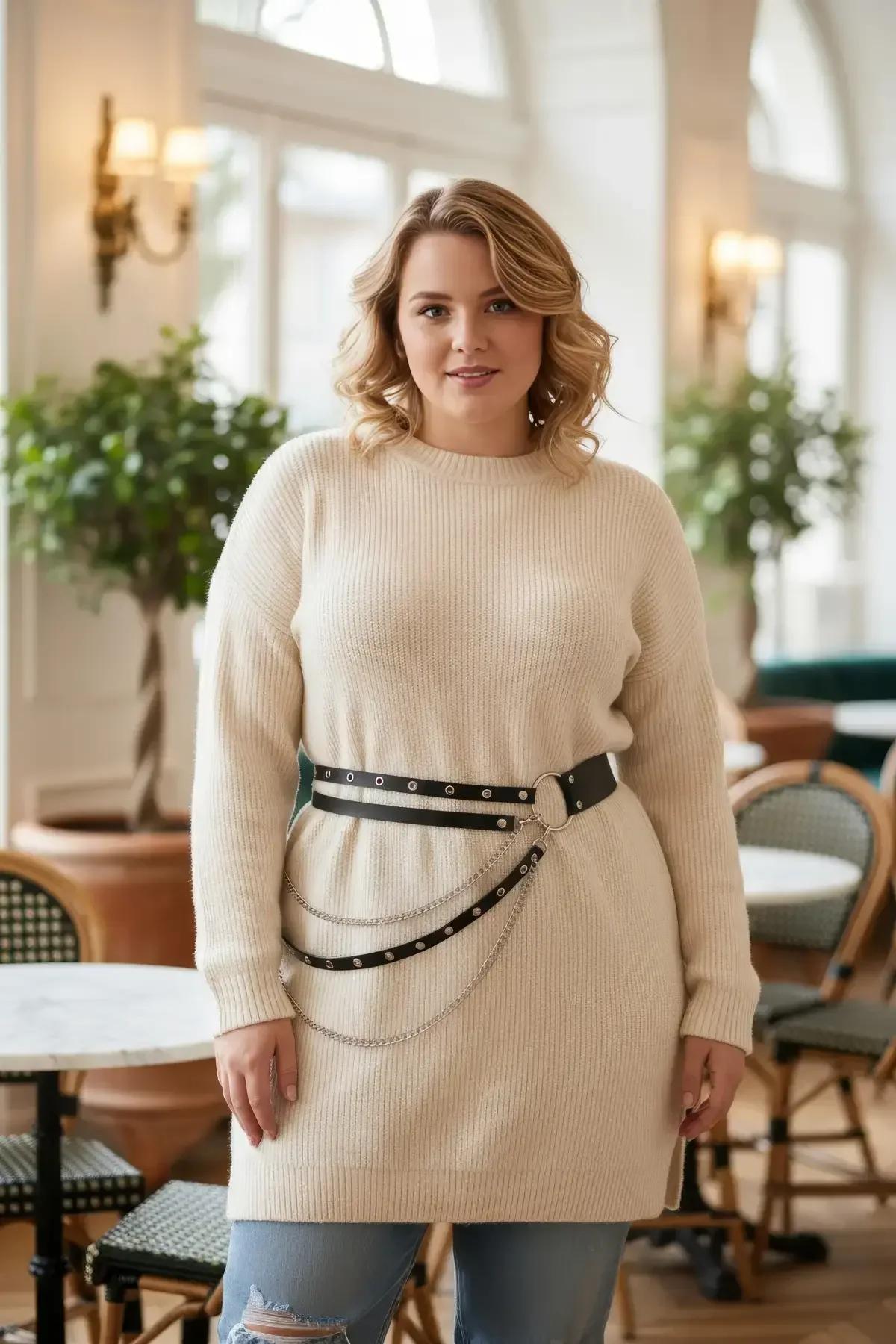 black faux leather double-row studded belt with silver O-ring and cascading chain drapes worn at waist over cream knit sweate