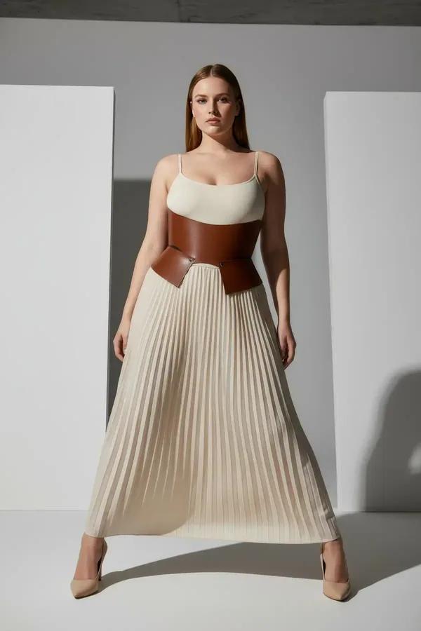 tan faux leather waspie waist cinch belt with angular front panels and gold stud hardware worn over cream tank top