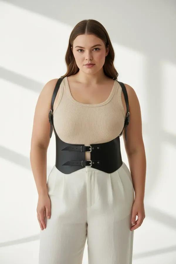black faux leather underbust harness waist cincher with silver buckle and shoulder straps worn over white tank top