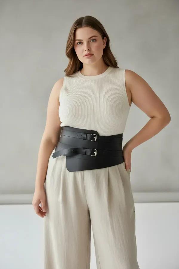 black faux leather waspie belt with asymmetric panel and dual silver buckles worn over cream tank top