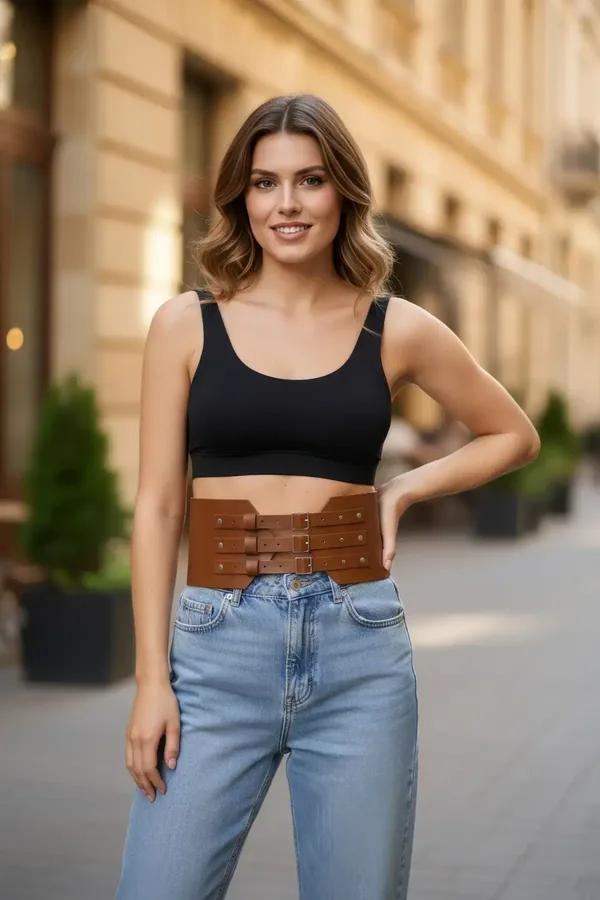 Taba geniş bel kemeri üç gümüş tokalı vegan deri korse, siyah crop top ve kot pantolon kombininde
