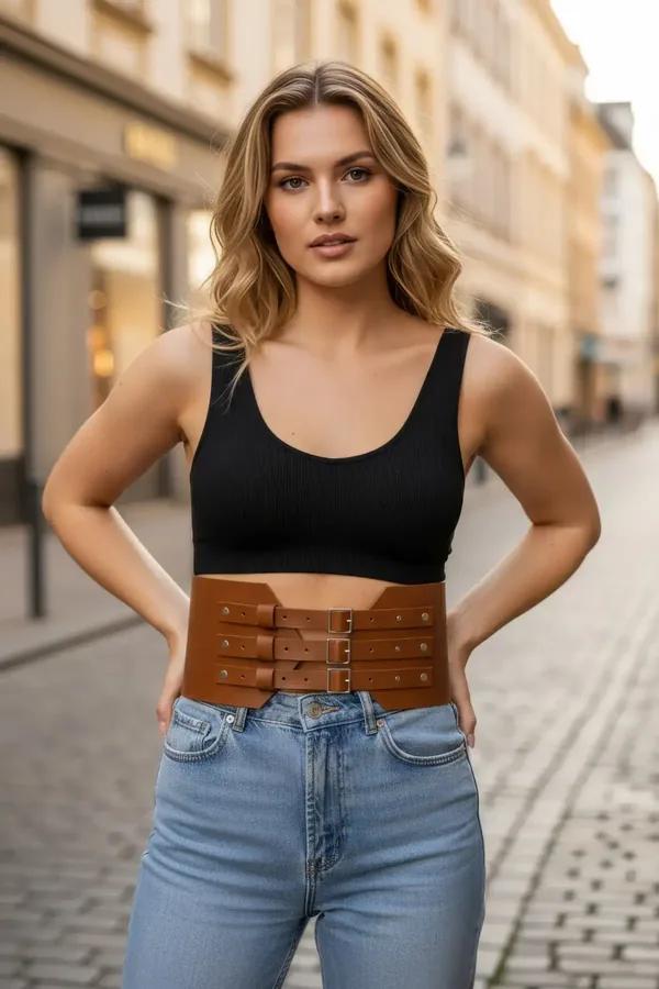 Taba geniş bel kemeri üç gümüş tokalı vegan deri korse, siyah crop top ve kot pantolon kombininde
