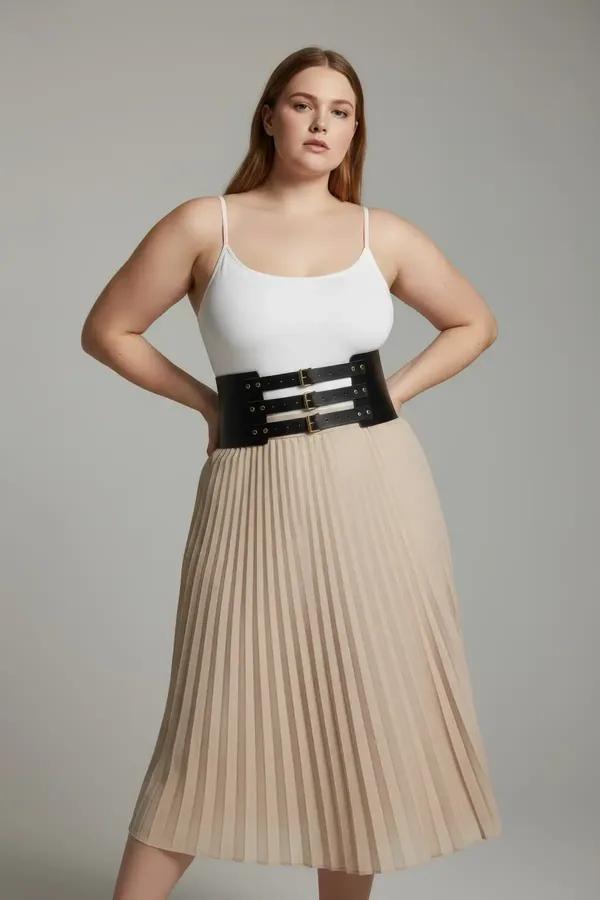 black wide faux leather waist harness with three gold-tone adjustable pin buckles worn over cream bodysuit and midi skirt