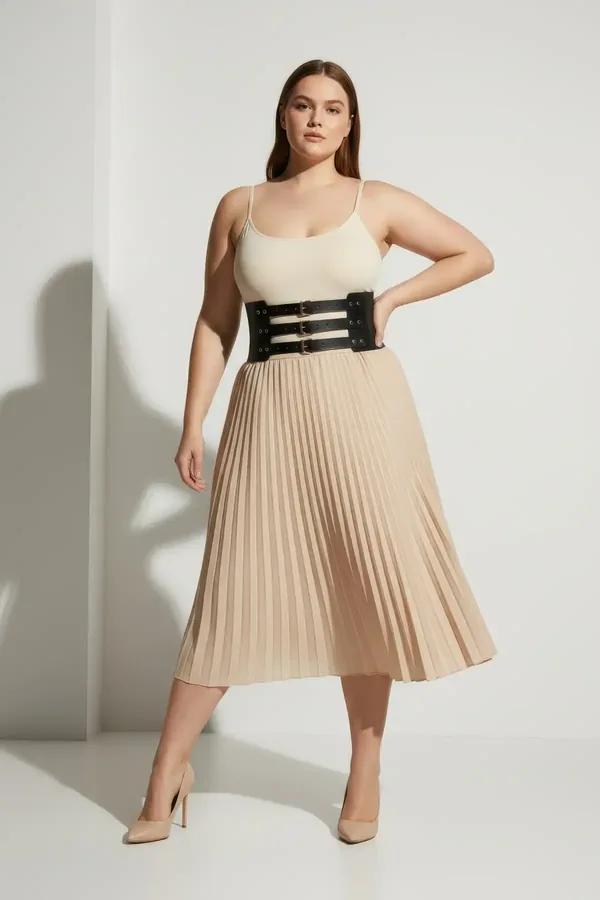 black wide faux leather waist harness with three gold-tone adjustable pin buckles worn over cream bodysuit and midi skirt