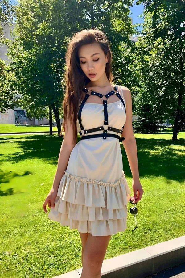 Siyah ince faux deri bantlı göğüs harness kemer, krem rüflü elbise üstünde X-cross O-ring detay