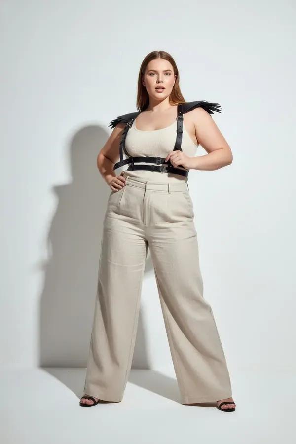 Black faux leather chest harness with structured fringe shoulder epaulettes and silver buckle hardware worn over cream crop t
