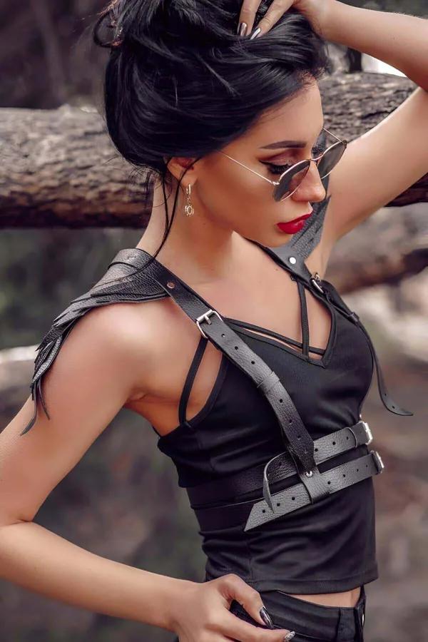 Siyah faux deri omuz kanatlı harness, çift gümüş tokalı bel bandı ve çapraz göğüs kayışı ile kadın modelde