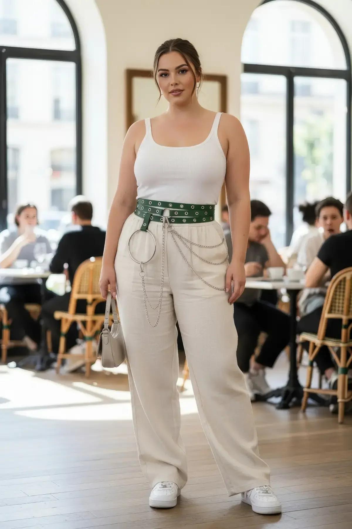 Wide green vegan leather grommet belt with silver O-ring chain drape worn at natural waist over cream wide-leg trousers