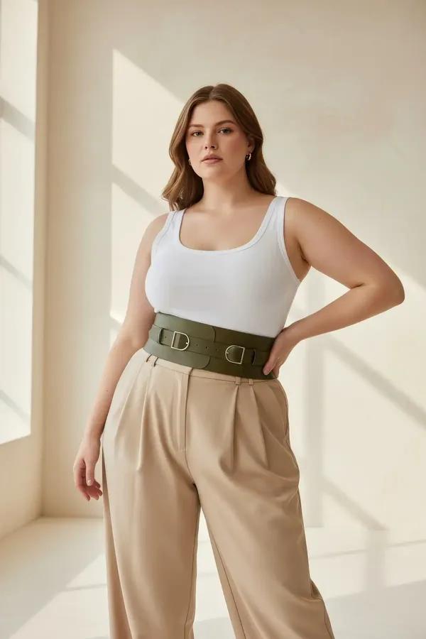 wide olive green vegan leather waspie waist belt with double silver D-ring buckles worn over white tank and beige trousers