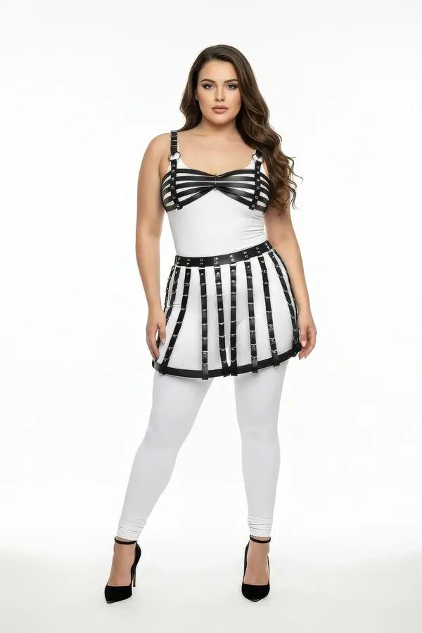 Black faux leather cage harness skirt with silver rivets on waistband worn over white leggings, vertical strap construction