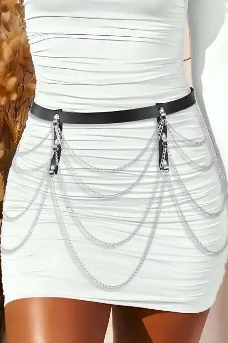 Siyah suni deri bant üzerine katmanlı gümüş zincir detaylı bel kuşağı beyaz mini etek kombininde