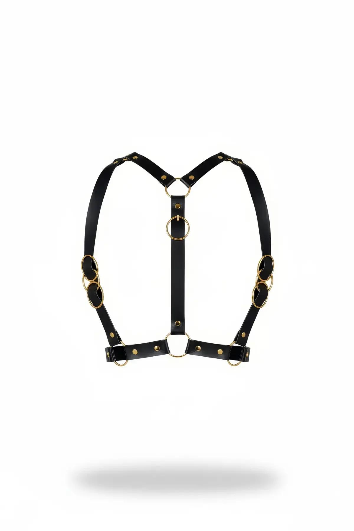black faux leather chest harness with stacked gold O-rings and brass rivets, Y-front silhouette on white background