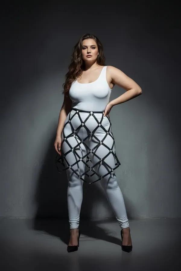 black faux leather geometric cage skirt harness with silver rivet detailing worn over white leggings