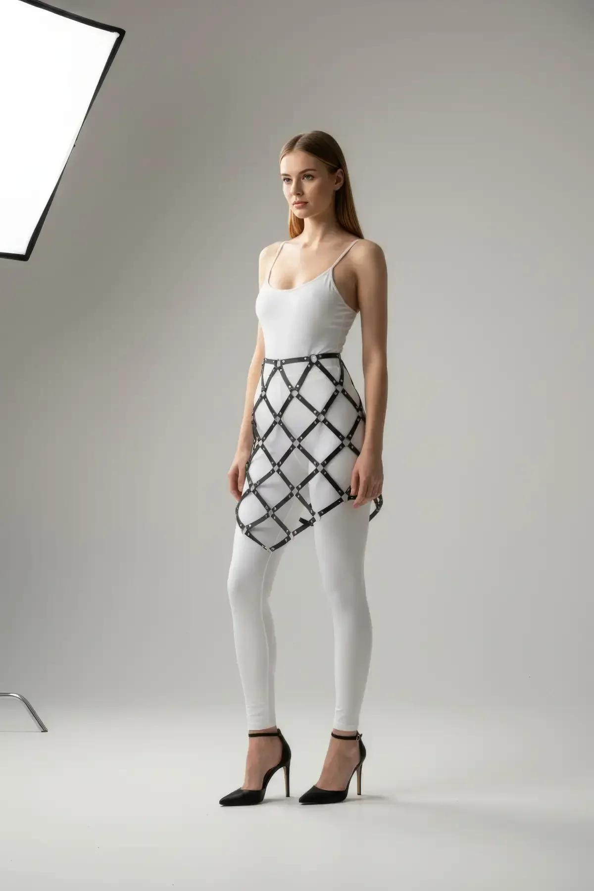 black faux leather diamond grid cage skirt harness with silver connector rings worn over white leggings