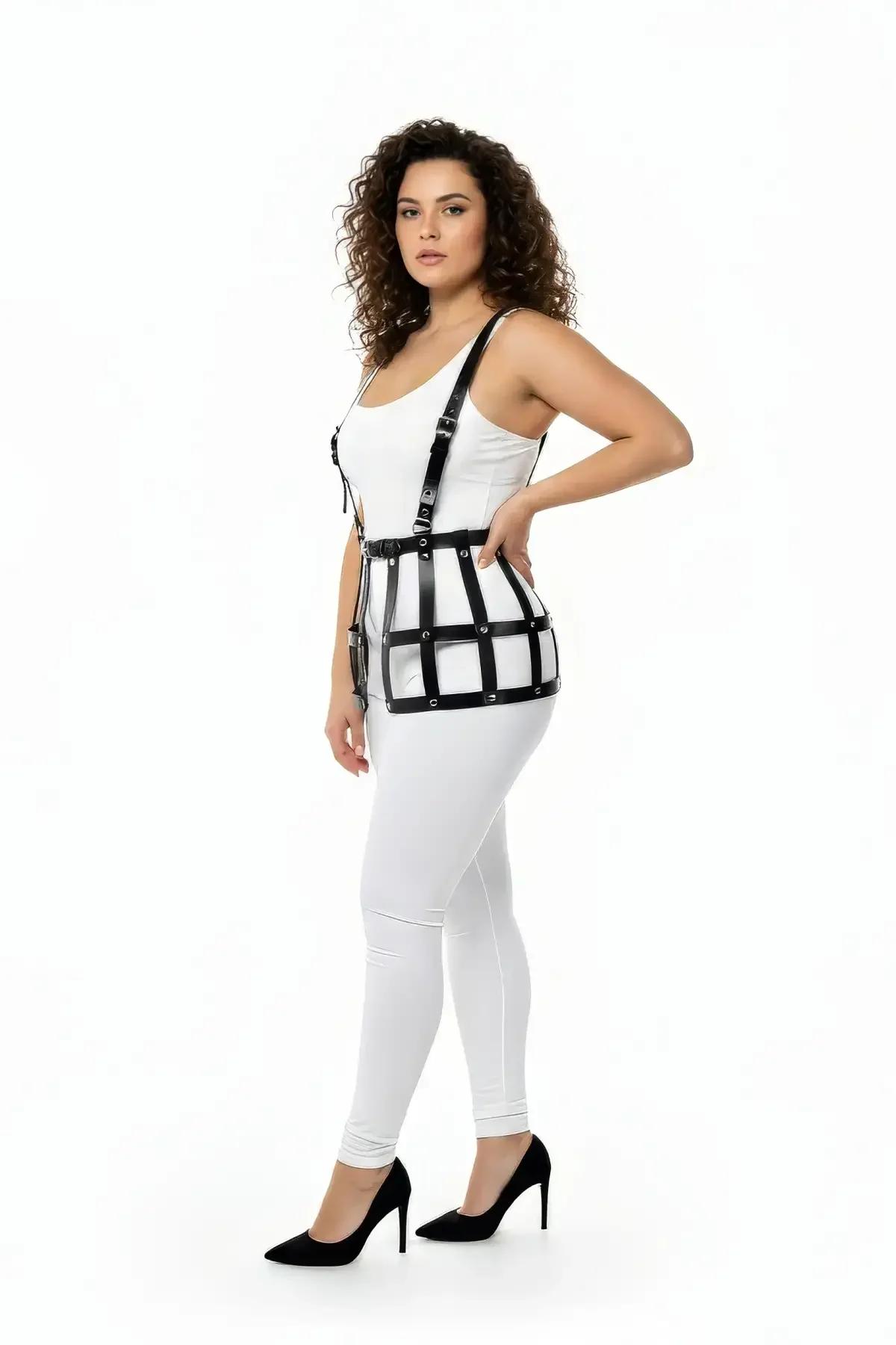 black faux leather caged waist harness with over-the-shoulder suspender straps and matte black O-ring hardware, worn over whi