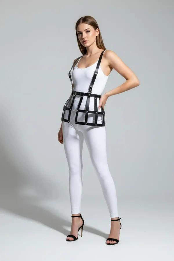 black faux leather cage skirt harness with shoulder straps and riveted geometric grid panels worn over white bodysuit