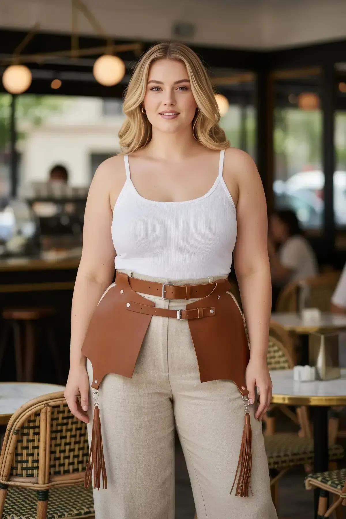 Tan faux leather waist harness with wide hip panels, dual silver buckle straps, and dangling tassels worn over white tank top